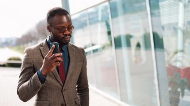 Ofis Merkezi yakınındaki bir akıllı telefon ayakta konuşurken Afrikalı-Amerikalı iş adamı. İş, insanlar, iletişim, teknoloji, eğlence ve yaşam tarzı kavramı