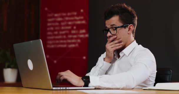 Fatigué de travailler sur l'ordinateur portable, le jeune homme d'affaires lève ses lunettes, se frotte les yeux, respire profondément. Un accro au travail, qui travaille dur, qui gagne de l'argent. Vue rapprochée — Video