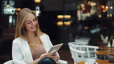 Gülümseyen kadın saçlarını bir alışveriş merkezinde oturan ve bir tablet okuma giderir