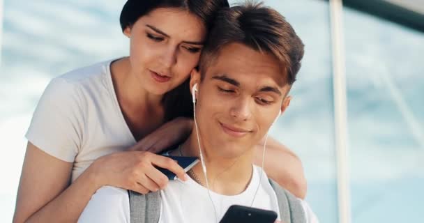 Pareja feliz enamorada usando smartphone. Pareja joven casada divirtiéndose en la espera de un vuelo en el aeropuerto. La mujer está tocando en la pantalla de la tableta — Vídeos de Stock