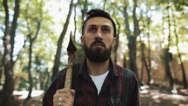 Madera barbuda andando con hacha. El hombre con gorra camina por el bosque en busca del árbol — Vídeos de Stock