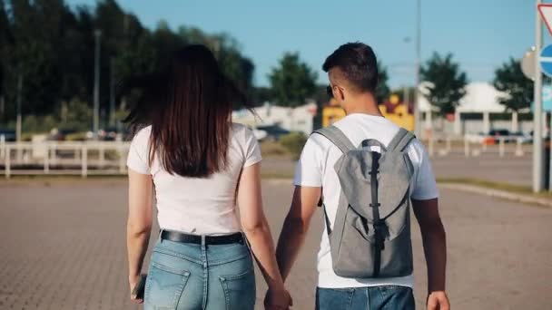 Jovem casal feliz vai com bagagem perto do aeroporto ou da estação ferroviária. O conceito de viagem, férias, feriados. Hora de verão, pôr do sol — Vídeo de Stock