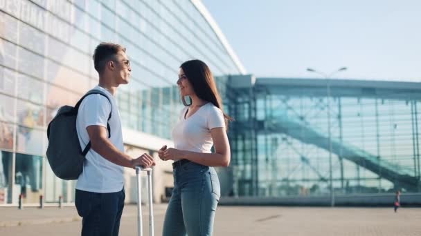 Belo casal apaixonado de pé perto do terminal do aeroporto, conversando uns com os outros. Negócios, contrato, ter um acordo. Descanso, viagem, comunicação, transporte. Estilo de vida bem sucedido — Vídeo de Stock