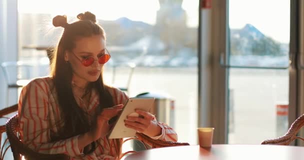 Jovem mulher lê algo em suas mesas sentadas à mesa no café fora — Vídeo de Stock