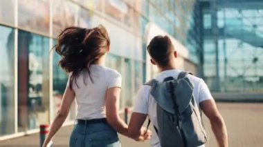 Sırt çantaları ve ellerinde pasaport ile mutlu genç çift Havaalanı ve tren istasyonuna çalıştırın. Seyahat, tatil, tatil kavramı. Yaz saati, gün batımı