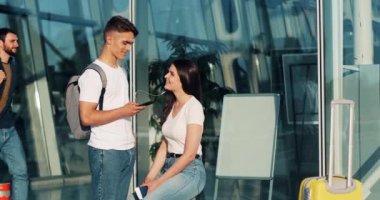 Mutlu çift aşık smartphone, kullanarak müzik dinlemek ve birbirinizle konuşun. Genç evli çift için bir uçuş havaalanında bekleyen eğleniyor