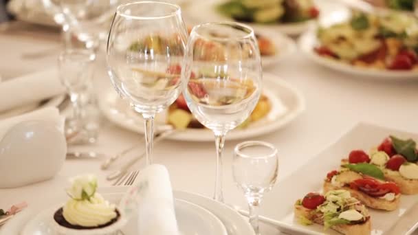 Mesa servida. Gafas sobre la mesa. Sala de banquetes. Banquete en el restaurante. Deliciosa comida en mesa de banquete en un restaurante de lujo — Vídeos de Stock