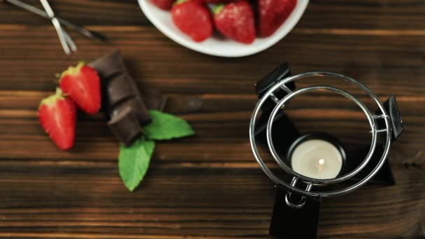 Las manos de los chefs ponen la fondue sobre la mesa. Fondue con fresas de chocolate sobre fondo de madera — Vídeo de stock