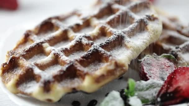 Porção de waffles belgas com morangos frescos no prato. Os chefs mão polvilhando sobremesa açúcar em pó — Vídeo de Stock