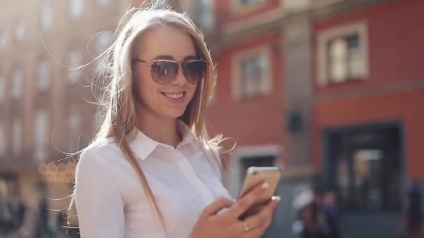 Hermosa mujer de negocios joven con camisa blanca y el uso de teléfono inteligente mientras camina en el centro de la ciudad negocio de Internet de verano fuera de la tecnología ojo primavera móvil cámara lenta calle feliz — Vídeos de Stock