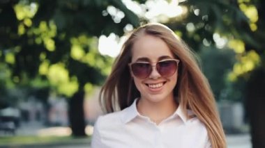 Çok gülümseyen genç kadın şık bir görünüm içinde güvenle güneş gözlüğü takıyor sokakta yürüyor. Hayat, aktif yaşam tarzı, moda blogger, podyum sevinci.