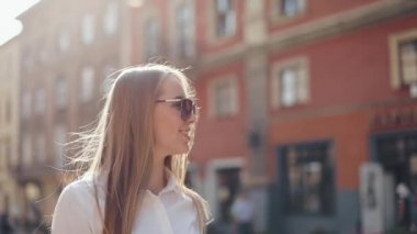 Güzel iş kadın güneş gözlüğü ile şehrin içinden yürüyerek gider. Şehrin varoşlarında arıyorum. Yaz saati