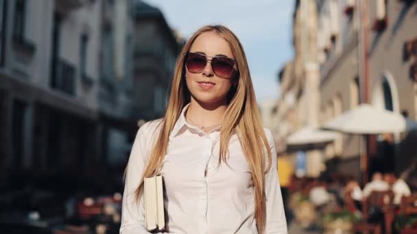 Mujer atractiva joven con gafas de sol sosteniendo libro y caminar por la ciudad vieja. Estudiante, educación, desarrollo, motivación, dama de negocios — Vídeos de Stock