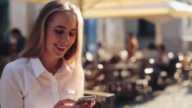 Çekici kadın sitiing smartphone online iletişim sosyal ağ bağlama seyir vasıl enterne kullanma bankta arka plan güneşli günde eski şehir binaları görüntüleme
