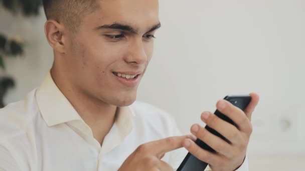 Joven hombre de negocios exitoso utilizando el teléfono inteligente móvil para comprobar la lectura de la notificación impactada noticia sorprendida cara asombrado joven en acogedora cafetería — Vídeos de Stock