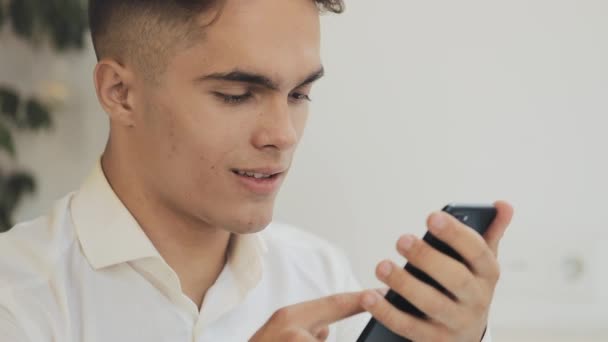 Giovane uomo d'affari felice utilizzando smartphone in caffè, colpo steadicam. Freelance, comunicazione, IT, concetto di persone di successo — Video Stock