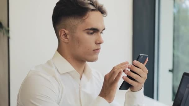 Jovem empresário bem sucedido usando celular inteligente para verificar a leitura de notificação notícias chocadas rosto surpreendido jovem no café acolhedor — Vídeo de Stock