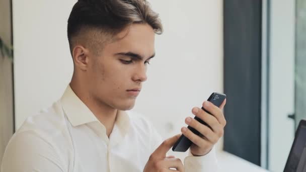 Jovem homem de negócios feliz usando smartphone no café, steadicam tiro. Freelance, comunicação, TI, conceito de pessoas de sucesso — Vídeo de Stock