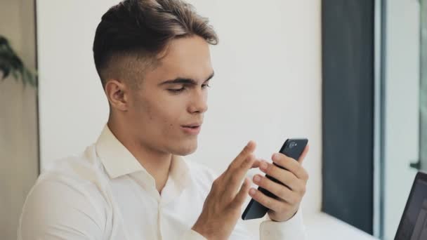 Giovane uomo d'affari felice utilizzando smartphone in caffè, colpo steadicam. Freelance, comunicazione, IT, concetto di persone di successo — Video Stock