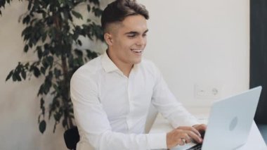 Yakışıklı genç işadamı pencerenin yakınındaki kafede bir dizüstü bilgisayar üzerinde çalışıyor. İş, kariyer, başarı, serbest meslek, iş arama kavramı