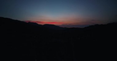 Şaşırtıcı turuncu günbatımında harika dağlar üzerinde uçan
