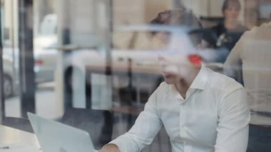 Mutlu genç iş bir dizüstü bilgisayarda çalışan bir kafede bir masada oturuyor. Evet jest, gösterilen laptop arıyorum kazanan zafer, zevk başarı, web üzerinde iyi haber kutlama yaptı