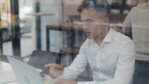 Glada unga företag sitter vid ett bord på ett café som arbetar på en bärbar dator. Vinnare tittar på laptop visar ja gest, fira framgångar, goda nyheter på webben, njuter av triumf, gjorde det — Stockvideo