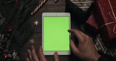 Erkek eller kaydırma, yeşil ekran ile beyaz tablet bilgisayarda sayfa yakınlaştırma. Chroma anahtar. Üstten görünüm. Dikey konum. Yılbaşı yeni yıl kavramı