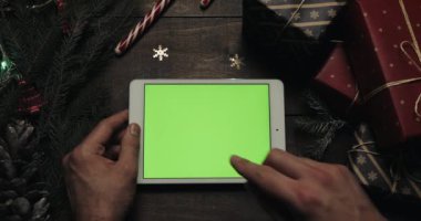 Erkek yeşil ekran beyaz tablet bilgisayarınızla sayfalarında dokunarak eller. Chroma anahtar. Üstten görünüm. Yatay konum. Yılbaşı yeni yıl kavramı