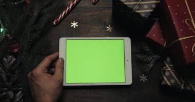 Kaydırma, dokunarak, yeşil ekran ile beyaz tablet bilgisayarda sayfa yakınlaştırma erkek eller. Chroma anahtar. Üstten görünüm. Dikey konum. Yılbaşı yeni yıl kavramı