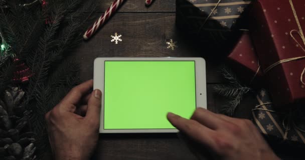 Mani maschili toccando pagine sul computer tablet bianco con schermo verde. Chiave cromatica. Vista dall'alto. Posizione orizzontale. Natale concetto di Capodanno — Video Stock