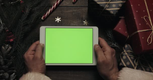 Férfi kezét megérinti oldalak a zöld képernyő fehér tabletta számítógép. Chroma-kulcs. Felülnézet. Függõlegesen a telefont. Karácsonyi-újévi koncepció