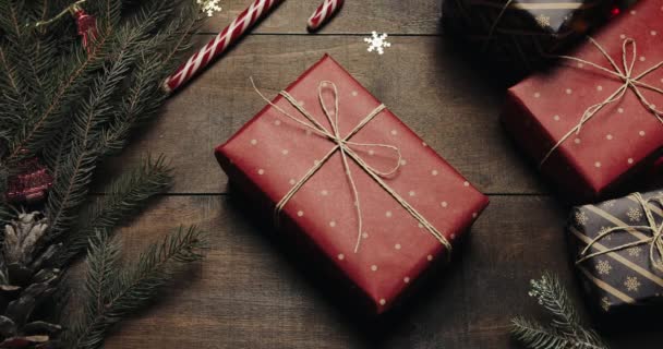 Table en bois marron décorée avec des trucs de Noël et des guirlandes. Des cadeaux sont sur la table. Vue du dessus — Video