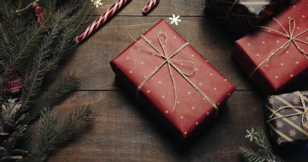 Vue de dessus. Table en bois marron décorée avec des trucs de Noël et des guirlandes. Des cadeaux sont sur la table. Les mains des hommes emportent un cadeau. Une autre personne l'en empêche — Video