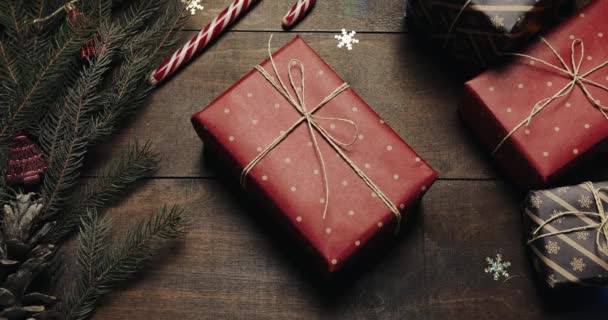Vista dall'alto. Tavolo marrone in legno decorato con roba natalizia e ghirlande. I regali sono sul tavolo. Le mani degli uomini portano via un regalo. Un'altra persona glielo impedisce. — Video Stock
