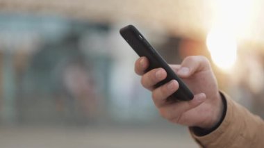 Elleri shopping mall yakınındaki sokakta smartphone kullanan genç adam. İletişim, online alışveriş, sohbet, sosyal ağ kavramı. Yakın çekim