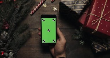 Erkek siyah smartphone ile yeşil ekran sayfalarında dokunarak eller. Chroma anahtar. Üstten görünüm. Dikey konum. Yılbaşı yeni yıl kavramı