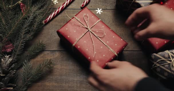 Male hands put give big New year present on style wooden background with New year decoration and Xmas tree with blurred blinking lights — Stock Video