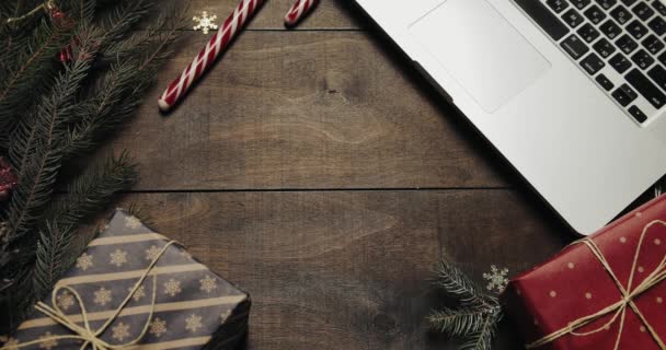 Bovenaanzicht. Mooie houten tafel met decoratie van de vakantie van Kerstmis. Mannelijke handen zet een geschenk op tafel. Bovenaanzicht concept van de kerst vakantie decoratie. Houten achtergrond — Stockvideo