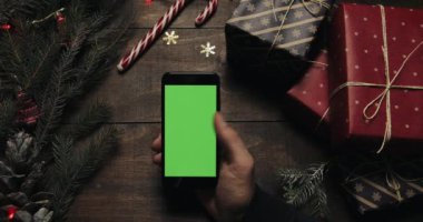 Erkek siyah smartphone ile yeşil ekran sayfalarında dokunarak eller. Chroma anahtar. Üstten görünüm. Dikey konum. Yılbaşı yeni yıl kavramı