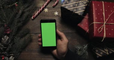 Erkek siyah smartphone ile yeşil ekran sayfalarında dokunarak eller. Chroma anahtar. Üstten görünüm. Dikey konum. Yılbaşı yeni yıl kavramı