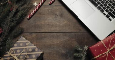 Üstten görünüm. Neşeli Noel ahşap arka plan. Tablo yeni yıl dekorasyon, dizüstü bilgisayar, hediyeler ve yanıp sönen ışıklar zemin döngü video ile Xmas ağacı.