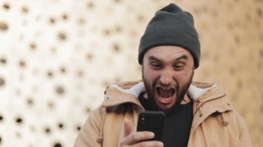 Spor zafer ya da iyi haber sokakta Alışveriş Merkezi yakınındaki bir akıllı telefon kullanarak kutluyor mutlu adam. Başarı durumunda satır bahis kazanmak kavramı