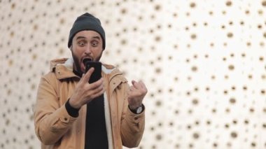 Spor zafer ya da iyi haber sokakta Alışveriş Merkezi yakınındaki bir akıllı telefon kullanarak kutluyor mutlu adam. Başarı durumunda satır bahis kazanmak kavramı