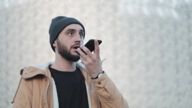 Adam cep telefonu açık, üzerinde sesli mesaj gönderme. O bir sonbahar ceket ve örme şapka giyiyor. İletişim, online alışveriş, sohbet, sosyal ağ kavramı