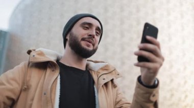 Mutlu genç adam görüntülü sohbet arkadaşlarınızla sohbet smartphone webcam holding sahip sakallı. Dışarıda