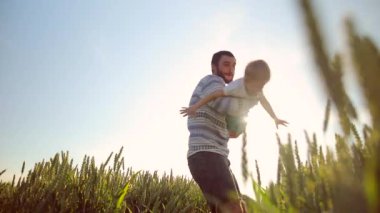 Baba ve oğul birlikte oynayan Close-up. Buğday sahada. Genç baba oğlunun elinde döner