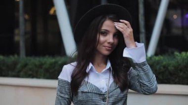 Kameraya bakarak ve gülümseyen iş merkezi arka plan üzerinde siyah şapkalı çekici genç kadın. Yakın çekim. Portre vurdu