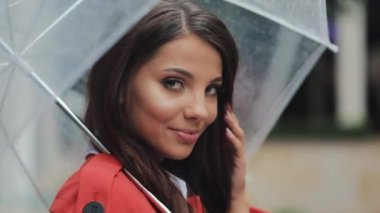 Kameraya bakarak City şemsiyesi altında gülümseyen kadın portresi. Bahar veya sonbahar günü