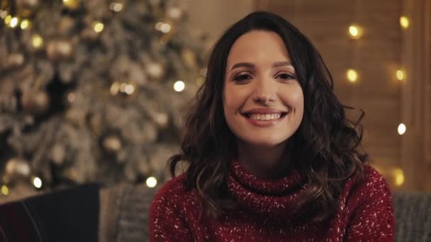 Aantrekkelijke vrouw op zoek en Smilling in de Camera op de achtergrond van de kerstboom. Slow motion — Stockvideo